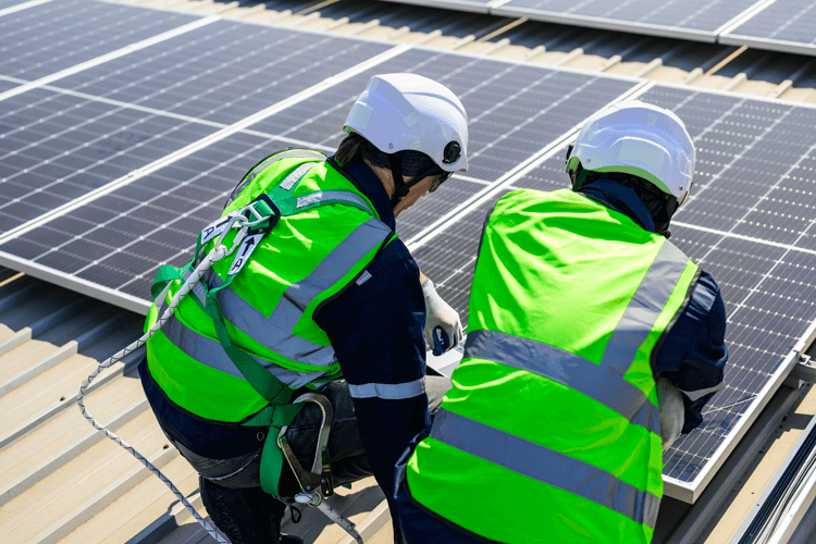 Due installatori certificati montano un impianto fotovoltaico sul tetto di una casa posizionando correttamente i pannelli solari.